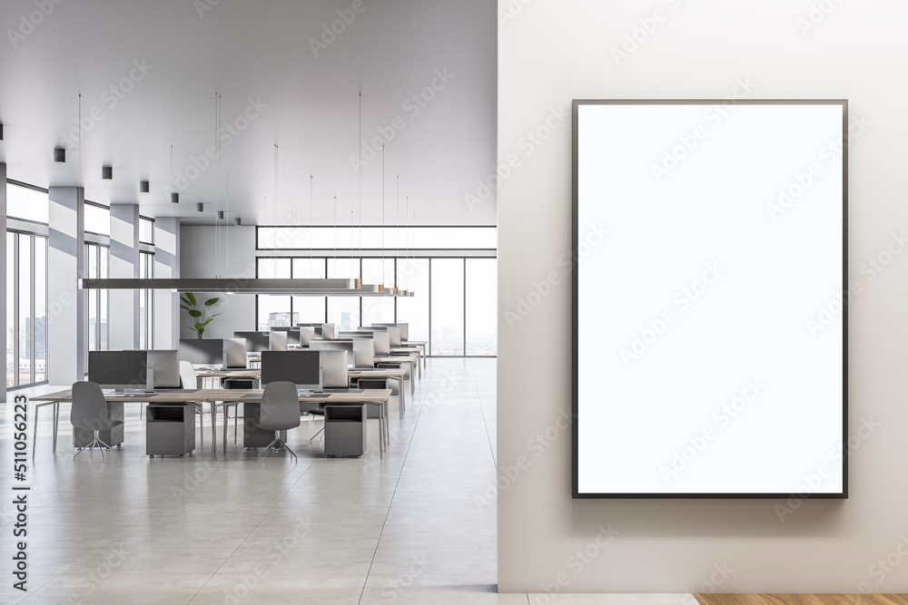 Blank white poster on light wall in spacious sunlit coworking office ...