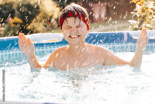 Portrait of smiling gen z Happy teen boy jumping in swimming pool at home backyard. Cute child toddler having fun enjoy summer time vacation laughing, yelling splashing water drops. Stay cooling off.