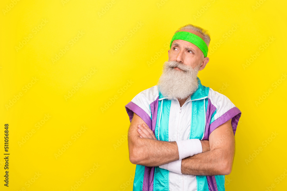 Photo of serious minded person folded arms look interested empty space advert isolated on yellow color background Photo of serious minded person folded arms look interested empty space advert isolated on yellow color background