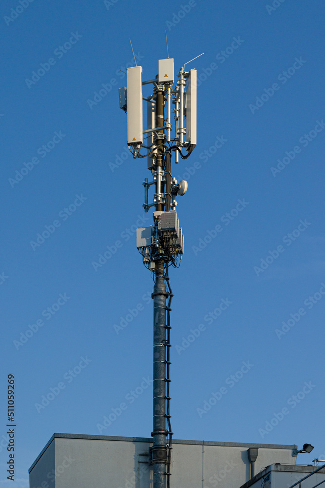 antenna mast for mobile radio communications mounted at a roof top in front of blue sky antenna mast for mobile radio communications mounted at a roof top in front of blue sky