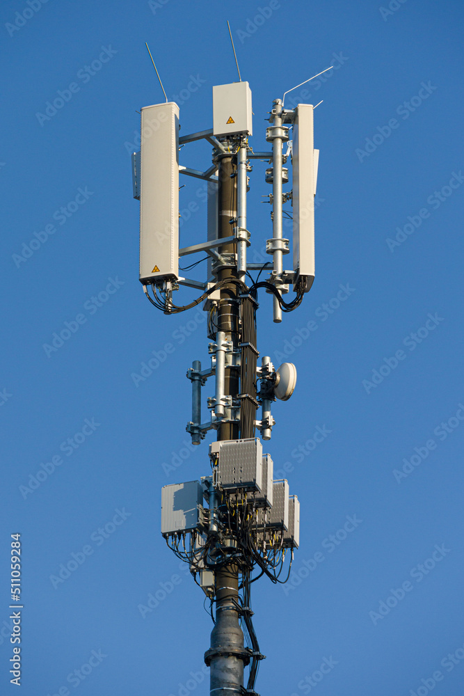 close-up of an antenna mast for cellular services mounted at a roof top in front of blue sky close-up of an antenna mast for cellular services mounted at a roof top in front of blue sky