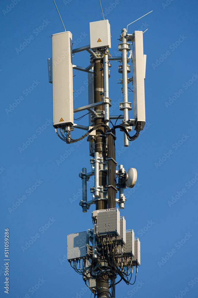 close-up of an antenna mast for mobile radio communications mounted at a roof top in front of blue sky close-up of an antenna mast for mobile radio communications mounted at a roof top in front of blue sky