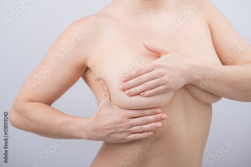 Caucasian woman self checks for breast cancer on white background. 