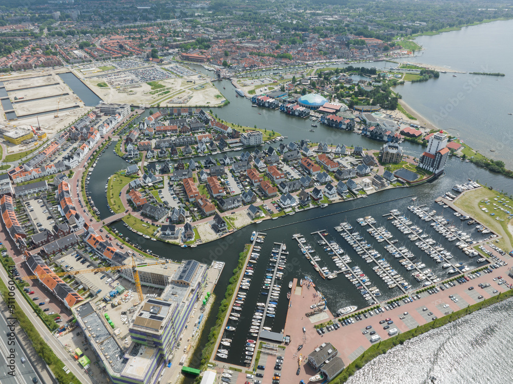 Obraz premium Harderwijk small village in the province of Gelderland in The Netherlands. Aerial drone of new build residential area and buildings in a harbour along the WOlderwijd.