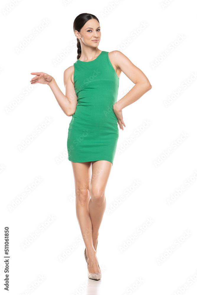 a young woman in a short green dress posing on white background a young woman in a short green dress posing on white background