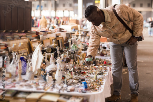 African American man chooses antiques on the flea market
