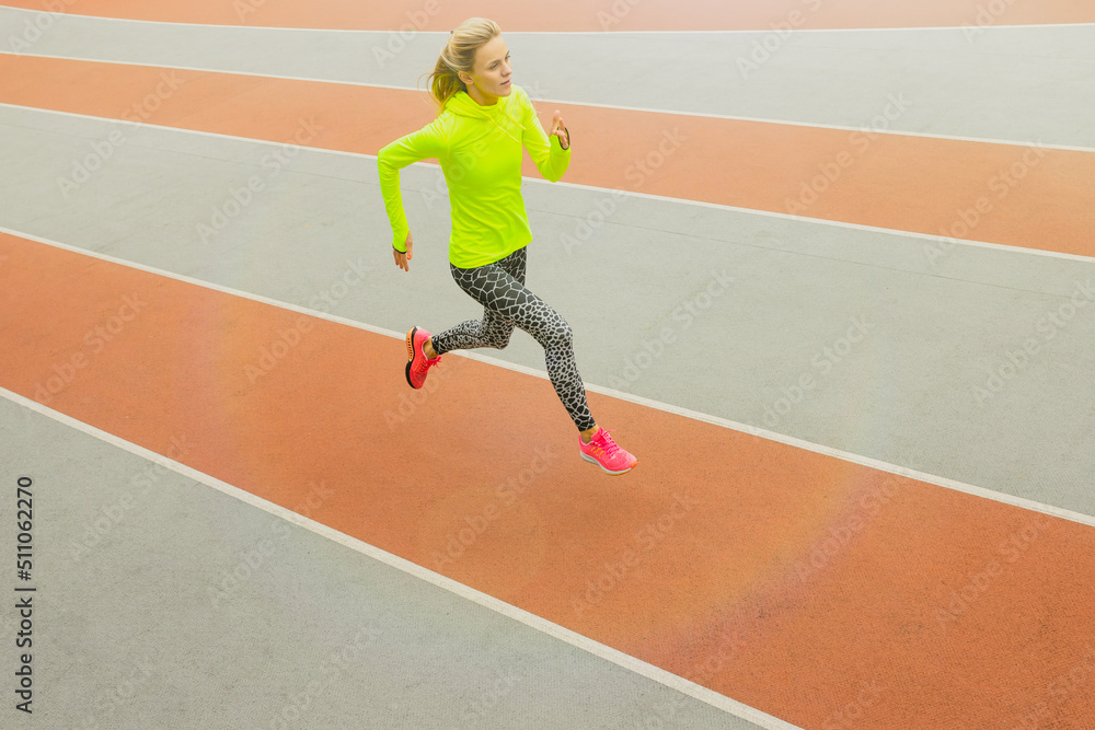 Obraz premium Top view of an athlete running on a treadmill. A young woman in a bright tracksuit. Competitions