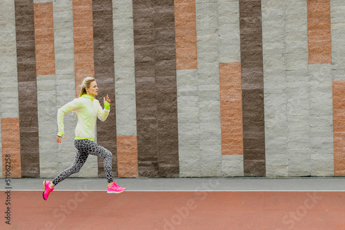 A female athlete during a workout outside. A young woman trains her running technique in an outdoor stadium