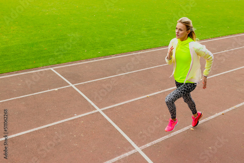 An athletic woman runs on the treadmill of an open stadium. Healthy lifestyle. Training outside