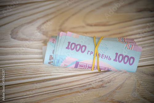 new Ukrainian hryvnia. 1000 hryvnia on wooden table bind with rubber tape to tube. money background and wealth concept photo