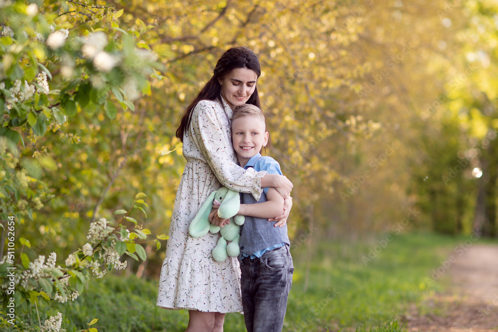 Fototapeta premium Mom with dark hair hugs her son and looks at him