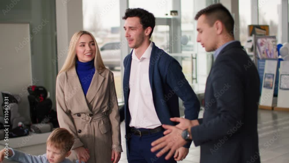 family car purchase, joyful parents with male child talking to salesman in auto showroom about buying new vehicle in shopping mall family car purchase, joyful parents with male child talking to salesman in auto showroom about buying new vehicle in shopping mall