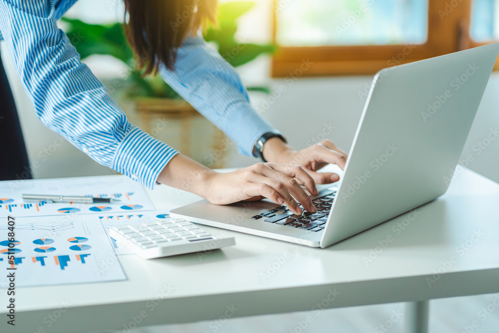 Business Woman standing working with laptop working on desk in modern office Business Woman standing working with laptop working on desk in modern office
