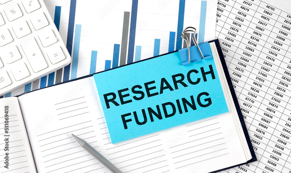 RESEARCH FUNDING on sticky note on notebook on the chart background RESEARCH FUNDING on sticky note on notebook on the chart background