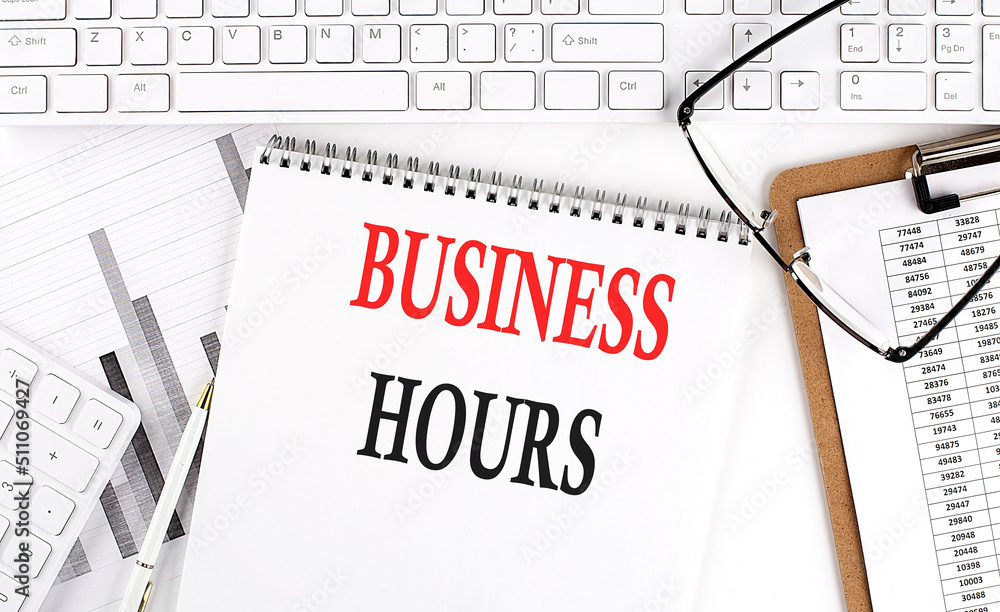 Text FLEXIBLE HOURS on Office desk table with keyboard, notepad and analysis chart on white background. Text FLEXIBLE HOURS on Office desk table with keyboard, notepad and analysis chart on white background.