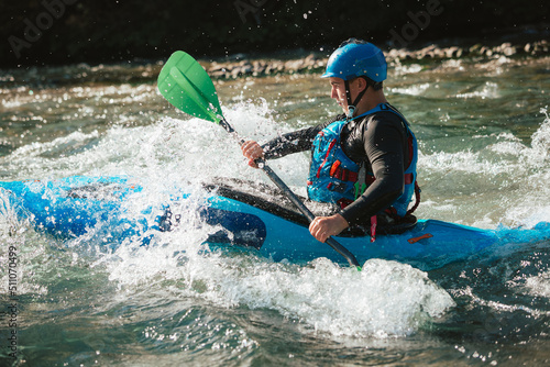 Young teenager cruising down whitewater rapids in a blue kayak, beautiful river nature on a sunny summer day, handheld shot.