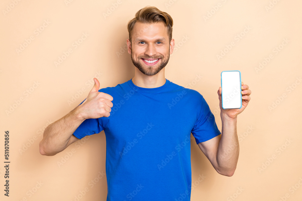 Photo of young man show thumb-up recommend perfect suggest mobile electronic isolated over beige color background Photo of young man show thumb-up recommend perfect suggest mobile electronic isolated over beige color background