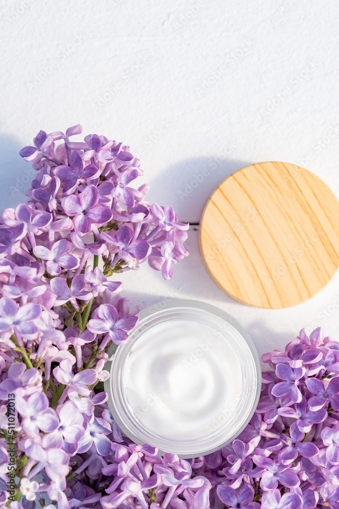 Jar of cream and lilac flowers on a white background, top view. Professional cosmetic products. Beauty and health concept. Plant-based cosmetics Jar of cream and lilac flowers on a white background, top view. Professional cosmetic products. Beauty and health concept. Plant-based cosmetics