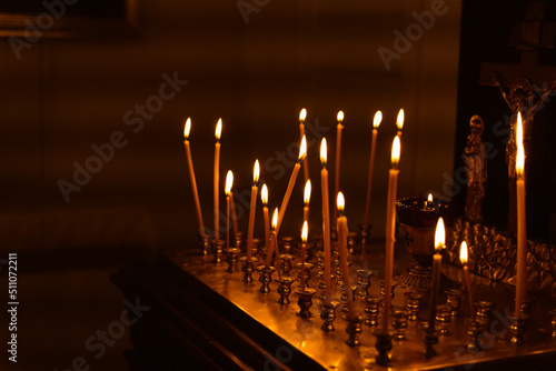 Memorial candles for the dead burn on the altar in the darkness of the temple next to the crucifixion of Jesus Christ, the concept of eternal memory of the departed