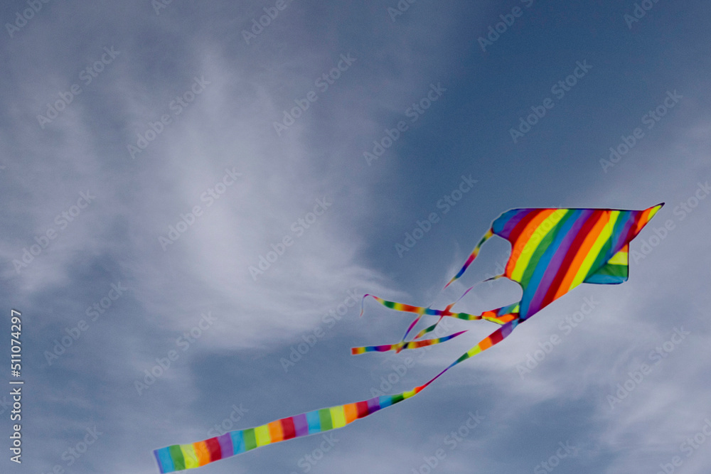 Colorful blue sky with white fluffy clouds and a flying colored kite Colorful blue sky with white fluffy clouds and a flying colored kite