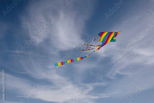 Colorful blue sky with white fluffy clouds and a flying colored kite