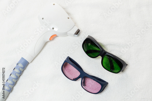 diode laser hair removal and glasses on a white cosmetic towel. body hair removal tools
