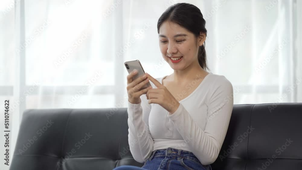Happy woman relaxing on comfortable couch, holding smartphone in hands. Smiling young lady chatting in social networks, watching funny videos, using mobile applications at home. Happy woman relaxing on comfortable couch, holding smartphone in hands. Smiling young lady chatting in social networks, watching funny videos, using mobile applications at home.