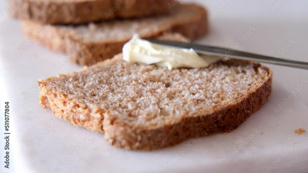 Spreading butter on whole grain yeast-free gluten-free bread close-up. Healthy breakfast Spreading butter on whole grain yeast-free gluten-free bread close-up. Healthy breakfast