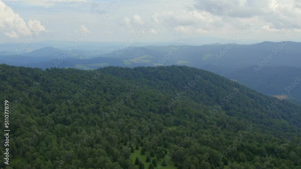 Green forest on mountains of Manzherok under white clouds, Altai, Siberia, Russia. Beautiful summer nature landscape at during daytime. Aerial view from a drone Green forest on mountains of Manzherok under white clouds, Altai, Siberia, Russia. Beautiful summer nature landscape at during daytime. Aerial view from a drone