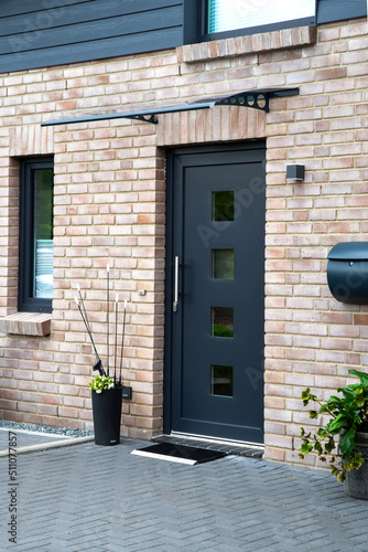Fotografie Elegant beige-brown brick house with gray entrance door and gray paved entrance