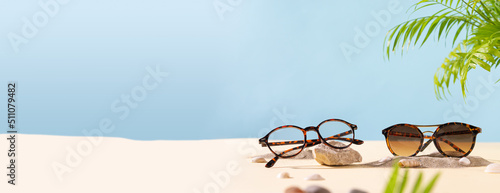 Sunglasses and glasses offer concept. Trendy sunglasses on a beach background with green palm leaves. Trendy Fashion summer accessories. Copy space. Summer sale banner. Optic store discount web line