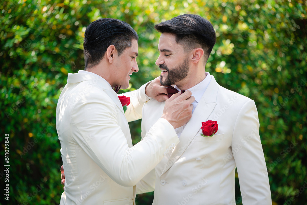 gay bride and groom wearing white suit with red rose in the pocket in LGBT gay wedding ceremony,romantic, selective focus. gay bride and groom wearing white suit with red rose in the pocket in LGBT gay wedding ceremony,romantic, selective focus.