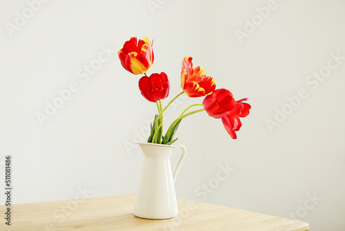 Elegant flowers in a vase background. Interior with a bouquet of red tulips. Minimalistic scandi style. Atmosphere of comfort and simplicity © Olga