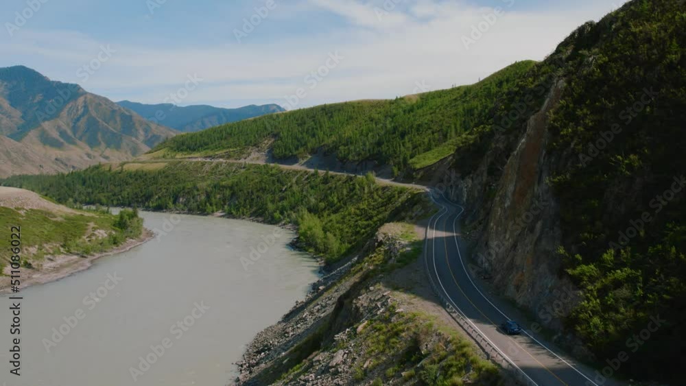 Cars on Chuya highway road between mountains and Katun river in Altai, Siberia, Russia. Beautiful summer nature landscape at during daytime. Aerial view from a drone Cars on Chuya highway road between mountains and Katun river in Altai, Siberia, Russia. Beautiful summer nature landscape at during daytime. Aerial view from a drone