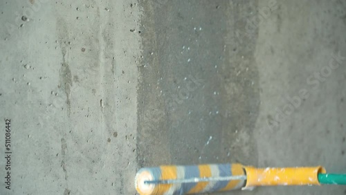 Priming a concrete wall with a paint roller, close-up. Selective focus