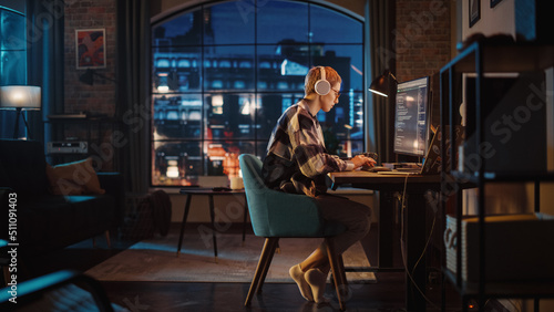 Obraz na płótnie Young Woman Writing Code on Desktop Computer in Stylish Loft Apartment in the Evening