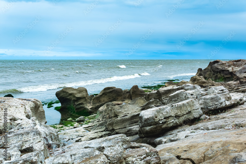 gently sloping rocky shore of the Caspian Sea with rounded rocks and algae on the stones