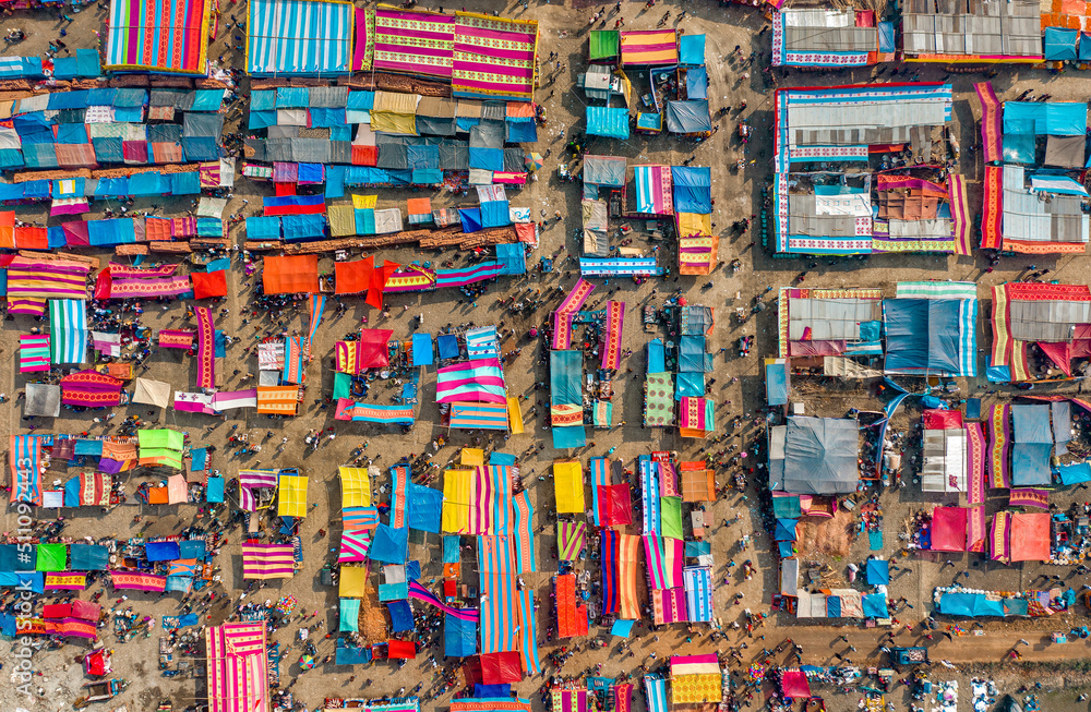 Aerial view of traditional village fair in Bangladesh. Colorful tents of temporary shops make it look like blocks of tetris game.  Portable ferris wheel