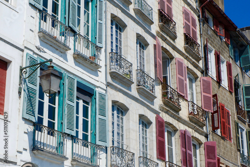 Colourful classical facades with windows shutters and tiny balconies downtown Bayonne, French Basque country, France