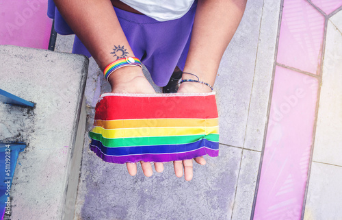 lgbt woman hands with lgbt flag in sunny day at outdoor park