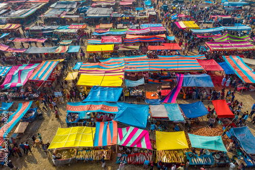 Aerial view of traditional village fair in Bangladesh. Colorful tents of temporary shops make it look like blocks of tetris game.  Portable ferris wheel