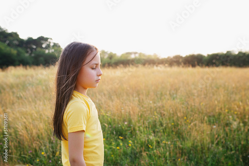 Happy little girl in the green meadow on a sunny summer day, child happiness