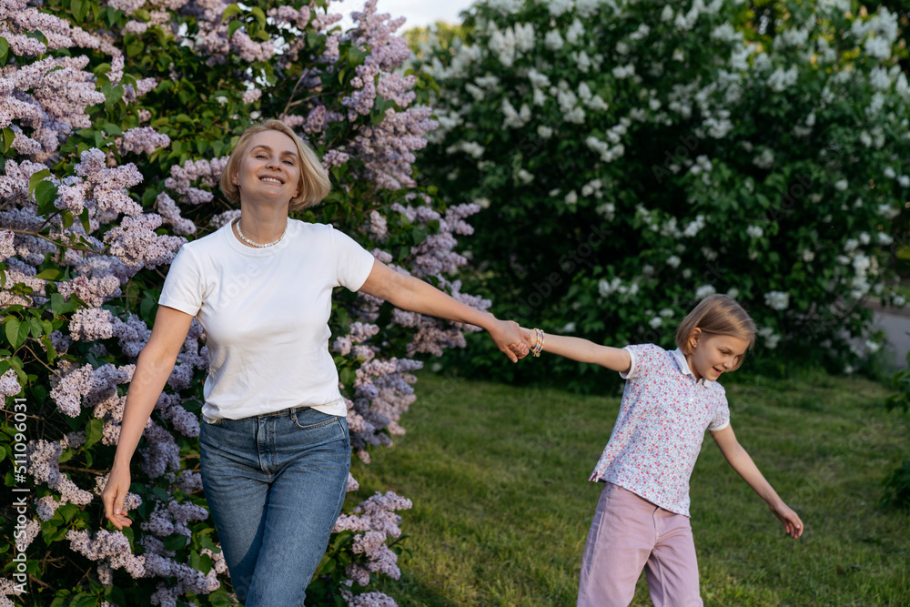 Fototapeta premium Mom and daughter are walking in a blooming park.