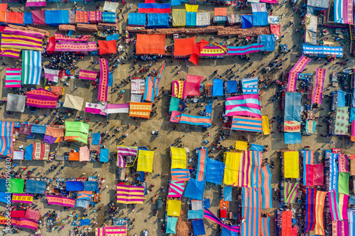 Aerial view of traditional village fair in Bangladesh. Colorful tents of temporary shops make it look like blocks of tetris game. Portable ferris wheel