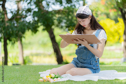Foto Portrait of attractive young pretty girl sitting in the public garden and drawing or painting a picture in summer season