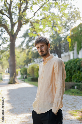 A European-looking man wearing an orange shirt and sunglasses. A tropical country in the hot summer. 