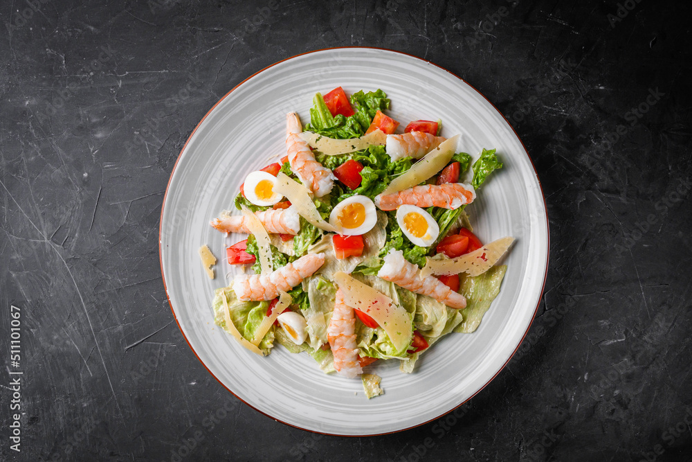 fresh salad with shrimp and parmesan on a black background fresh salad with shrimp and parmesan on a black background