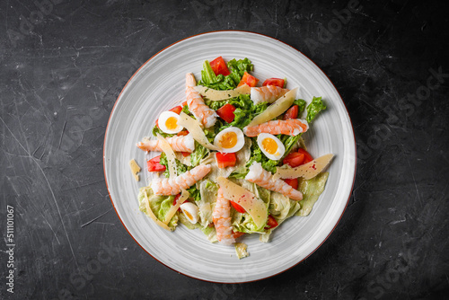 fresh salad with shrimp and parmesan on a black background