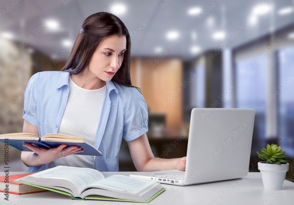 Business And Education Concept. Smiling young woman sitting at desk working on laptop Business And Education Concept. Smiling young woman sitting at desk working on laptop