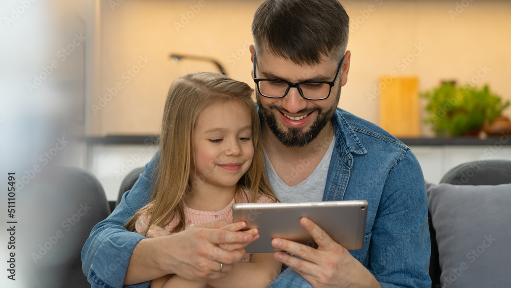 Happy family, father and little child use digital tablet sitting at home. Computer games, surfing internet, social media, buy in online store Happy family, father and little child use digital tablet sitting at home. Computer games, surfing internet, social media, buy in online store